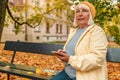 Senior 50s woman walking outdoors in autumn spring park using mobile phone. Royalty Free Stock Photo