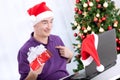 Senior santa holding present and using a computer