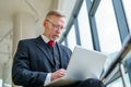 Senior serious businessman standing near window with panoramic city view Royalty Free Stock Photo