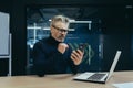 Senior serious gray-haired male businessman sitting in the office at the desk and using a mobile phone. Reads news Royalty Free Stock Photo