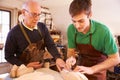 Senior shoemaker training apprentice to make shoe lasts