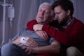 Sick man sleeping in his son`s arms at hospital bed Royalty Free Stock Photo