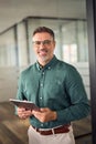 Senior smiling businessman holding tablet standing in office. Vertical portrait. Royalty Free Stock Photo