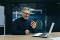 Senior smiling gray-haired male businessman sitting in the office at the desk and using a mobile phone. Reads news Royalty Free Stock Photo