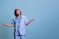 Senior specialist nurse doing i don t know sign in studio with blue background