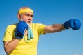 Senior sportive man in boxing stance doing exercises with boxing gloves. Elderly man hitting punching bag. Senior men