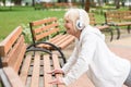 senior sportive woman in headphones training near benches