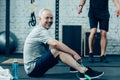 senior sportsman resting while young sportsman training with skipping rope