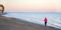 Senior sportswoman running at the beach in Spanish coasts. Athletic old woman practices physical activity, works out, training in