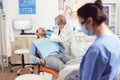 Senior stomatologist holding sterilized dental tools talking with sick patient