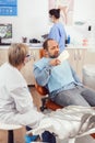 Senior stomatologist woman finishing dental surgery for man patient