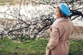 Senior stylish woman walking in spring blooming garden by river admiring nature landscape. Mother`s day