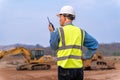 Senior supervisor engineer in his work cloths communicating to his working staff through walkie talkie at construction site