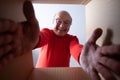 Senior surprised man unpacking, opening carton box and looking inside. Royalty Free Stock Photo