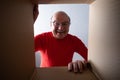 Senior surprised man unpacking, opening carton box and looking inside. Royalty Free Stock Photo