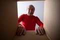 Senior surprised man unpacking, opening carton box and looking inside. Royalty Free Stock Photo