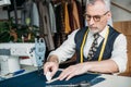 senior tailor making pattern on cloth with piece of chalk