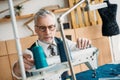 senior tailor touching spool of thread on sewing machine Royalty Free Stock Photo