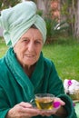 A senior takes her cup of tisane in an open air spa studio