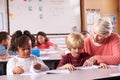 Senior teacher helping elementary school pupil in class Royalty Free Stock Photo