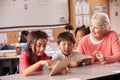 Senior teacher helping elementary school pupils using tablet Royalty Free Stock Photo