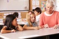 Senior teacher helping pupils in elementary school lesson