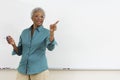 Senior teacher pointing while gesturing against white board in classroom Royalty Free Stock Photo