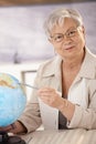 Senior teacher pointing at globe Royalty Free Stock Photo