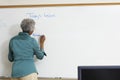 Senior Teacher Writing On Whiteboard Royalty Free Stock Photo