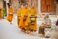 Senior Thai woman offers sticky rice to Buddhist monks in the morning at the street in Chiang Khan, Thailand.