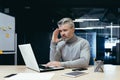 Senior thinking businessman working inside office with laptops, man thinking about important financial decision