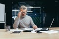 Senior thinking businessman working inside office with laptops, man thinking about important financial decision