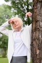 senior tired woman resting near tree