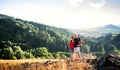 Senior tourist couple with backpacks hiking in nature, resting.