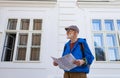 Senior tourist exploring new city, interesting places. Elderly man holding paper map, looking for the route. Solo