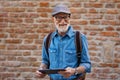 Senior tourist exploring new city, interesting places. Elderly man holding tablet and looking for the route. Traveling