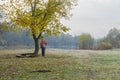 Senior tourist standing under autumnal tree at at Vorskla riverside