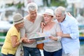 Senior tourists looking at map and tablet in town