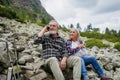 Senior tourists sitting on rocks and looking at the distant nature through binoculars. Royalty Free Stock Photo