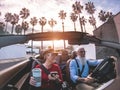 Senior trendy couple inside a convertible car on holiday time - Mature people having fun doing a road trip during vacation -