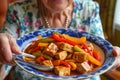 senior with a vibrant dish of stirfried tofu and bell peppers