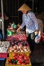 Senior Vietnamese woman in conical hat buying vegetables at the street market, Nha Trang, Vietnam