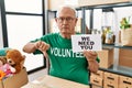 Senior volunteer man holding we need you banner with angry face, negative sign showing dislike with thumbs down, rejection concept Royalty Free Stock Photo