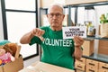 Senior volunteer man holding your donation matters with angry face, negative sign showing dislike with thumbs down, rejection