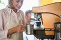 Senior waitress using coffeemaker