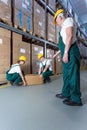 Senior warehouse worker controlling young co-workers