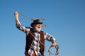 Senior western cowboy throwing lasso rope. Bearded wild west man with brown jacket and hat catching horse or cow. Rodeo Royalty Free Stock Photo