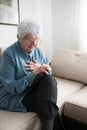 Senior white-haired woman having heart attack while reading a book at home