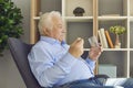 Serious senior man taking prescribed medication sitting in an armchair in the living-room Royalty Free Stock Photo