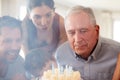 Senior white man celebrating with his family blowing out the candles on birthday cake, close up Royalty Free Stock Photo